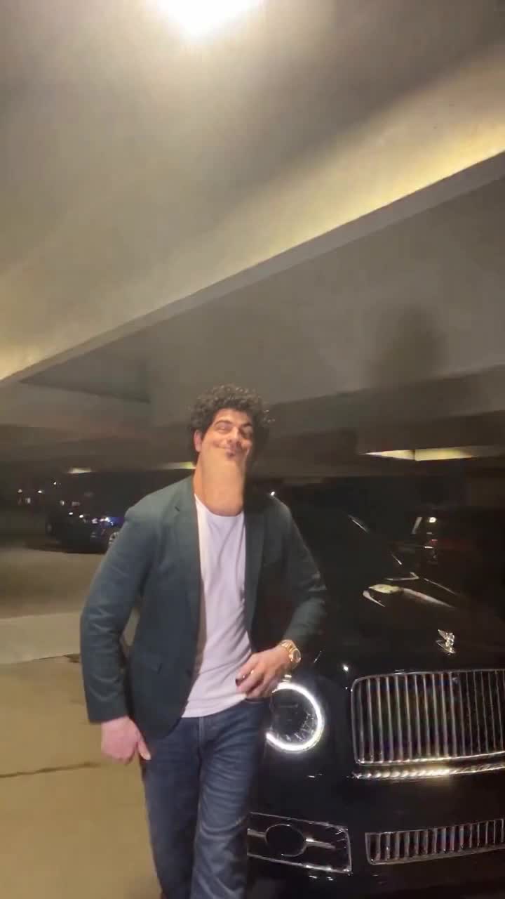 Alon parody dancing beside a luxury car in a parking garage