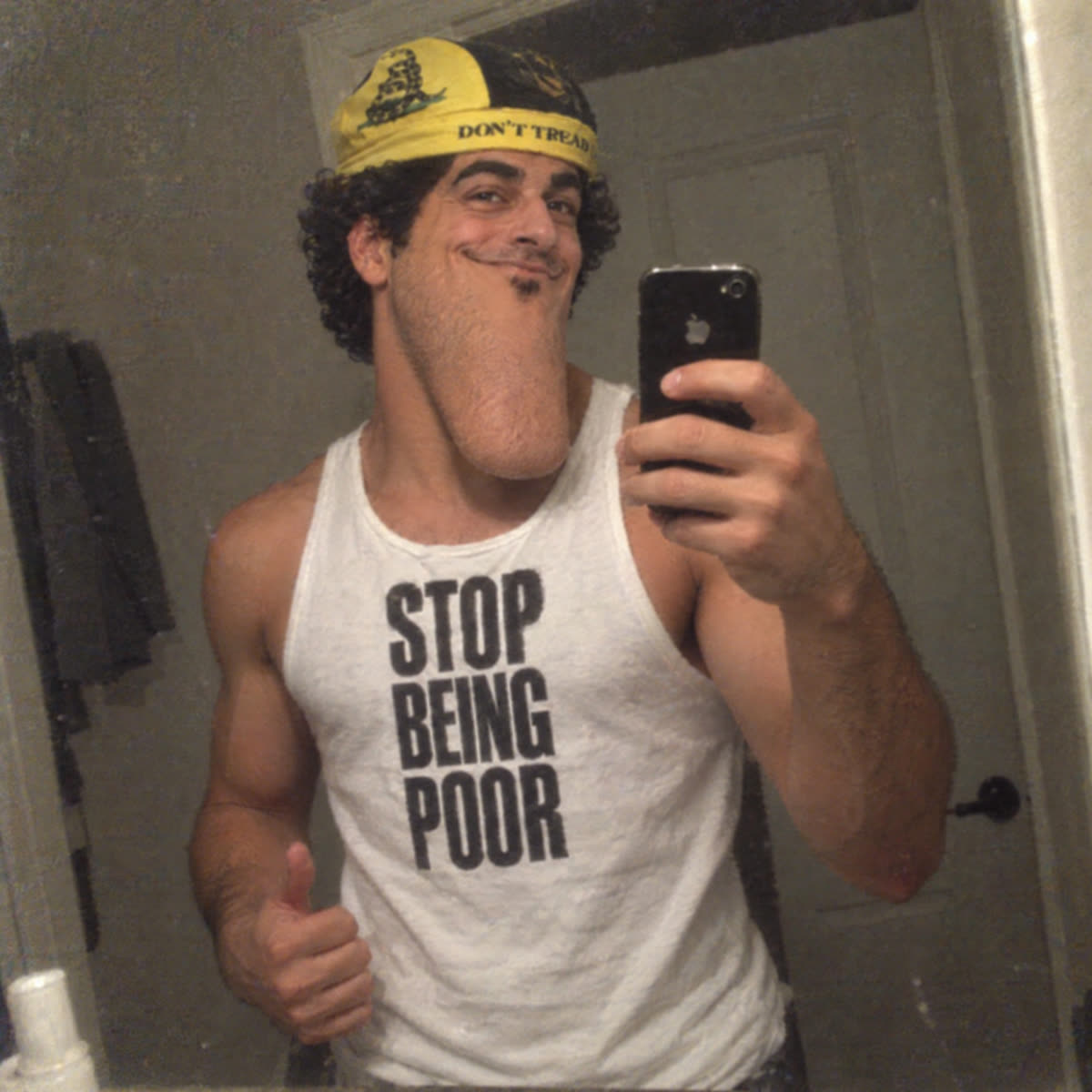 Long-chin Alon parody taking a mirror selfie in a Stop Being Poor tank top